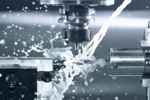 Close-up view of a CNC machine operated by BS Designs featuring precise metalworking with coolant spray.